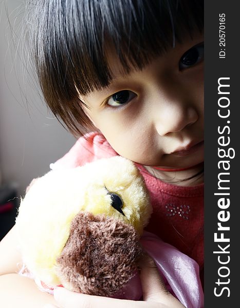 Bright picture of adorable chinese girl Holding the Toy dog near the windows. Bright picture of adorable chinese girl Holding the Toy dog near the windows