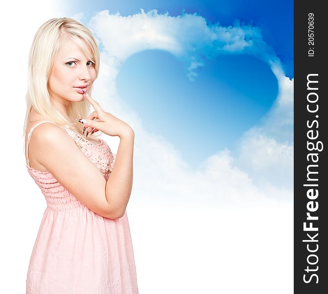 Young beautiful blonde on a background of clouds in the shape of a heart