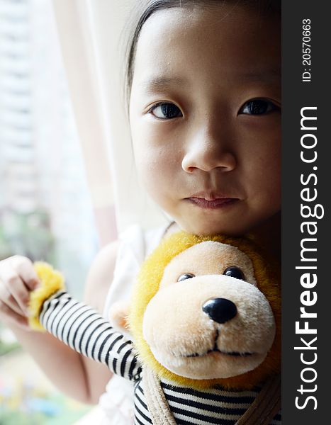 Bright picture of adorable chinese girl Holding the Toy Monkey near the windows. Bright picture of adorable chinese girl Holding the Toy Monkey near the windows