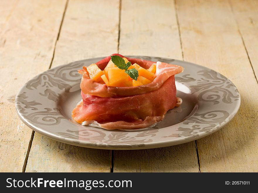 Photo of delicious sliced bacon with melon inside on wooden table. Photo of delicious sliced bacon with melon inside on wooden table