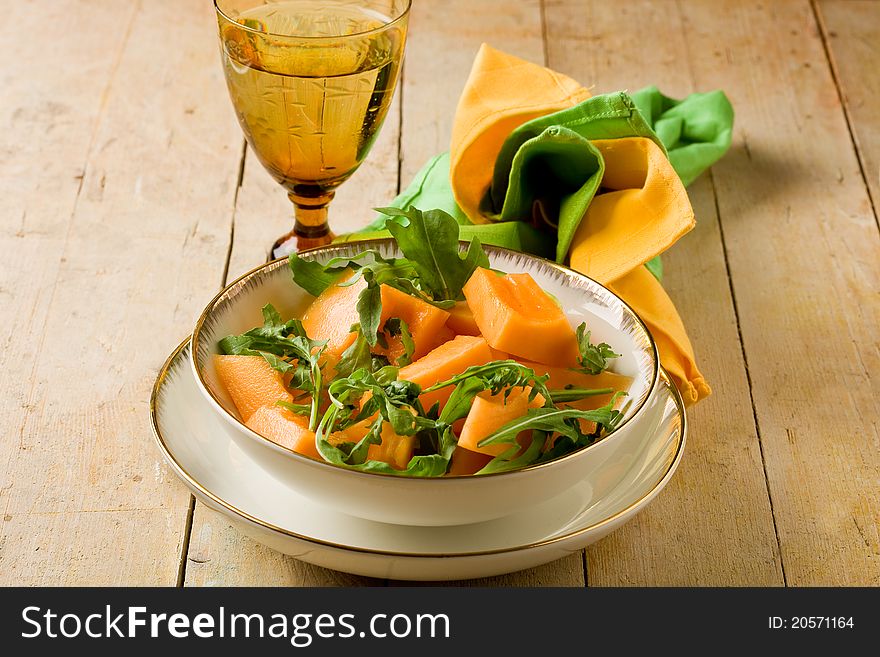 Photo of delicious melon and arugula salad on wooden table