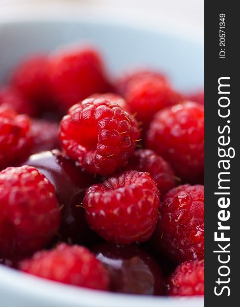 Fresh raspberries and cherries in a bowl. Close up (shallow dof).