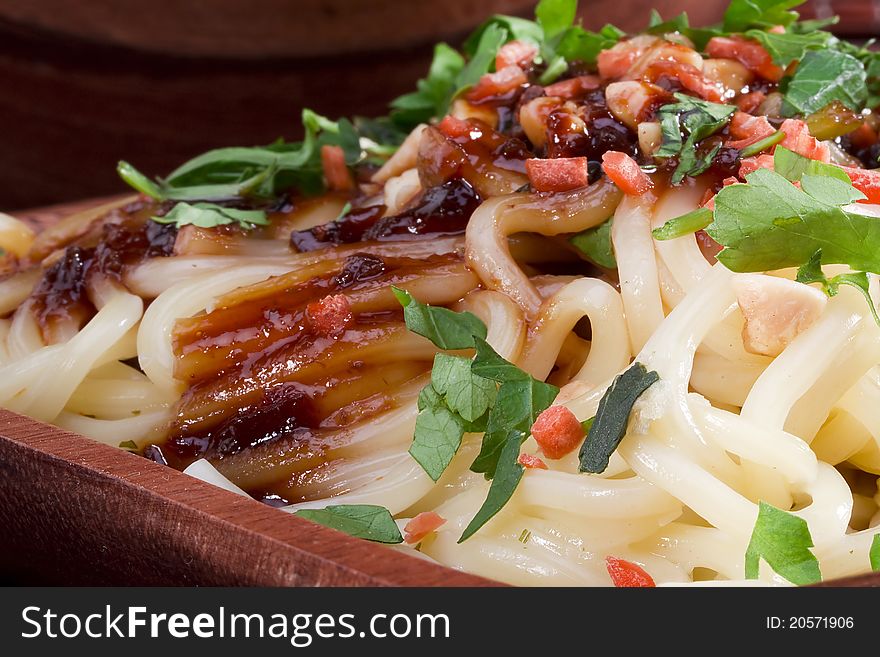 Freshly prepared Asian noodles on a brown wooden plate.