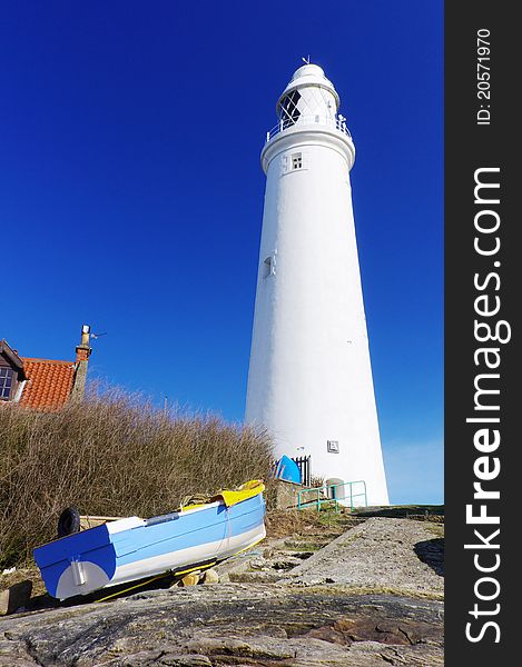 Close up of lighthouse and blue boat matching blue sky. Close up of lighthouse and blue boat matching blue sky