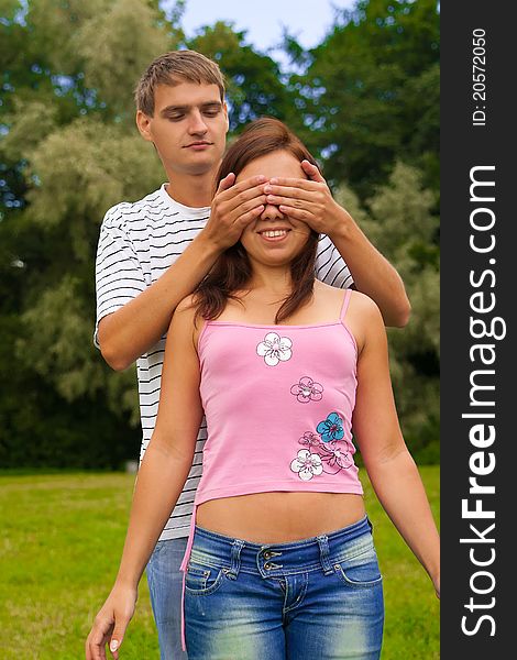 Young man closing her girlfriend eyes by hands. Young man closing her girlfriend eyes by hands