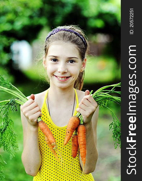 An image of a little girl with orange carrots. An image of a little girl with orange carrots