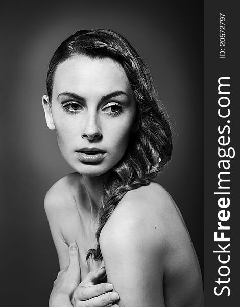 Close-up monochrome portrait of caucasian young woman with beautiful hairstyle on grey background. Close-up monochrome portrait of caucasian young woman with beautiful hairstyle on grey background