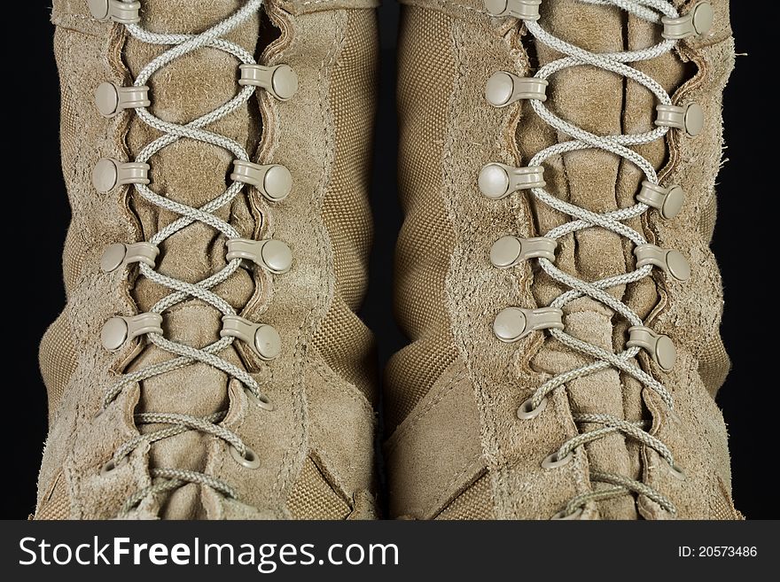 Close-up of tan leather Army combat boot laces on black background. Close-up of tan leather Army combat boot laces on black background.