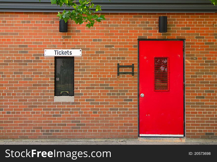 Ticket window and red painted door on the brick background. Ticket window and red painted door on the brick background
