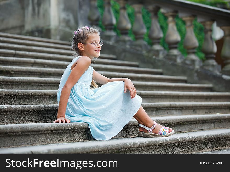 Cute beautiful girl sits on on the stairs in a park