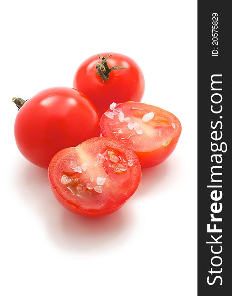 A few cherry tomatoes. One of them is cut and it is salt. On a white background. A few cherry tomatoes. One of them is cut and it is salt. On a white background.