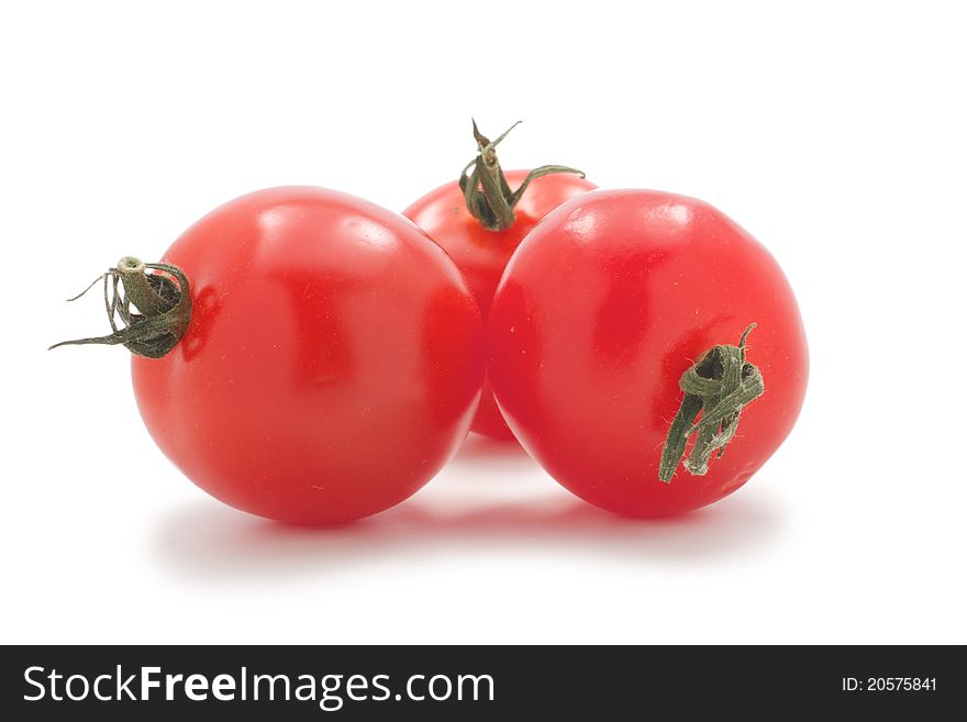 Cherry tomatoes with green tails, lie group. Their three. On a white background. Cherry tomatoes with green tails, lie group. Their three. On a white background.