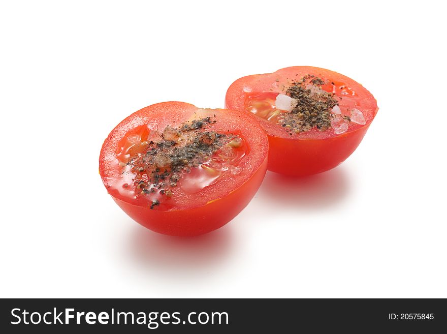 A few cherry tomatoes. One of them is cut and it is salt and pepper. On a white background. A few cherry tomatoes. One of them is cut and it is salt and pepper. On a white background.