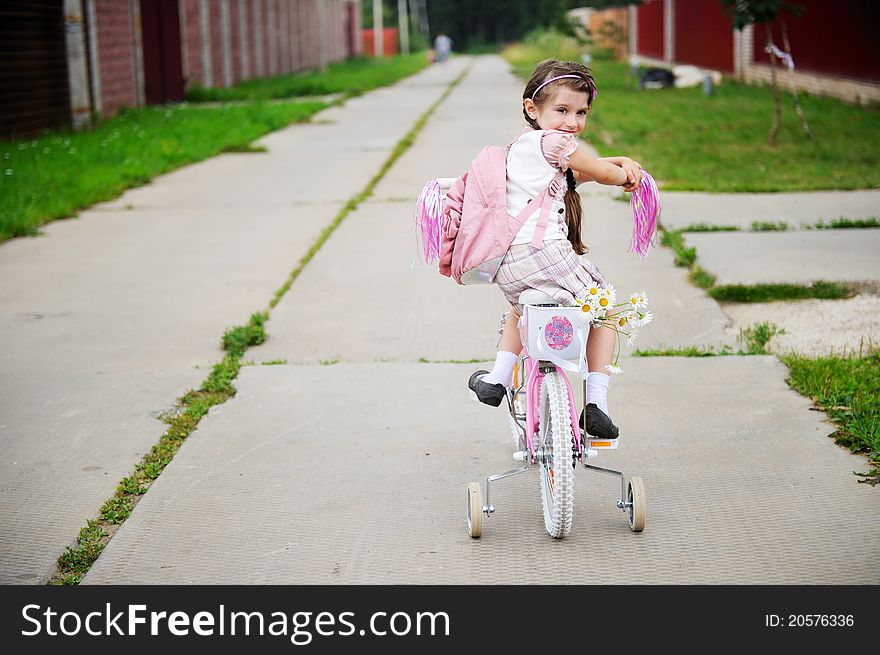 Young School Girl With Pink Bagpack On A Bicycle