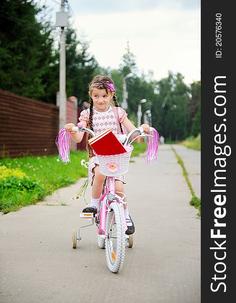 Young school girl with bagpack rides her pink bike to school. Young school girl with bagpack rides her pink bike to school