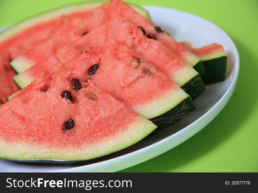 Watermelon white plate on a green background. Watermelon white plate on a green background