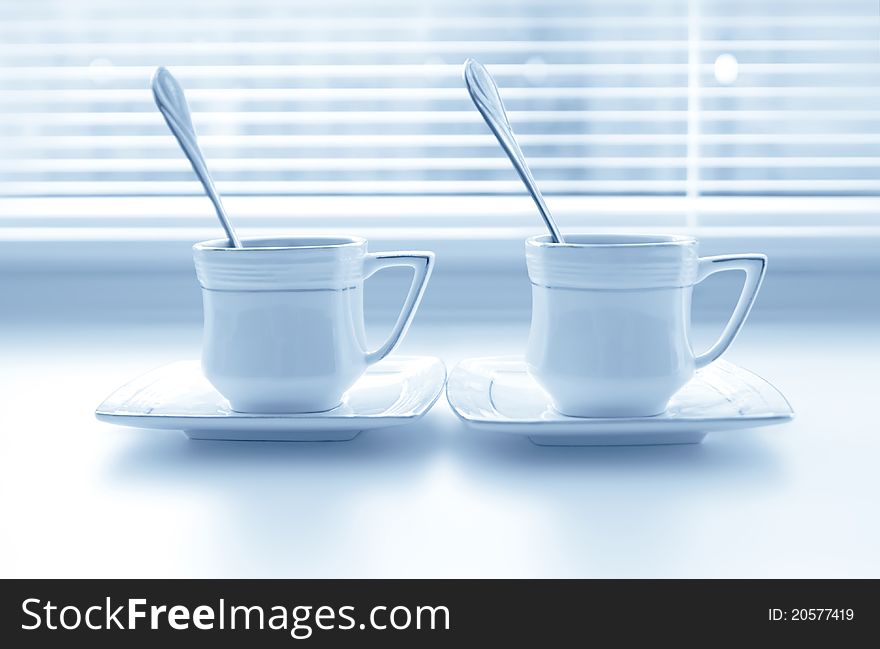 Two cups of coffee on the white windowsill with shutters