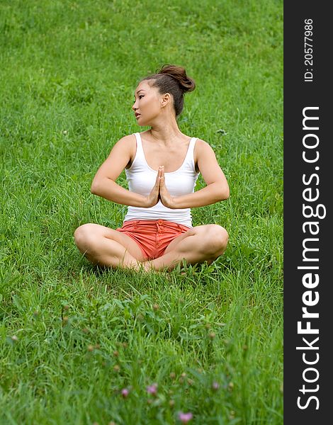 Girl meditating on meadow in park