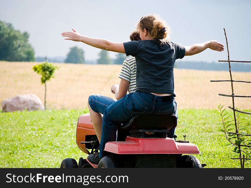 Boy and girl enjoy driving a tractor through a green field