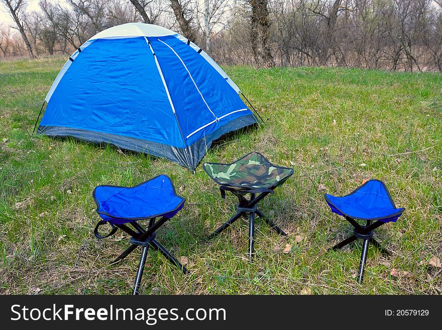 Tourist tent and chairs on green meadow