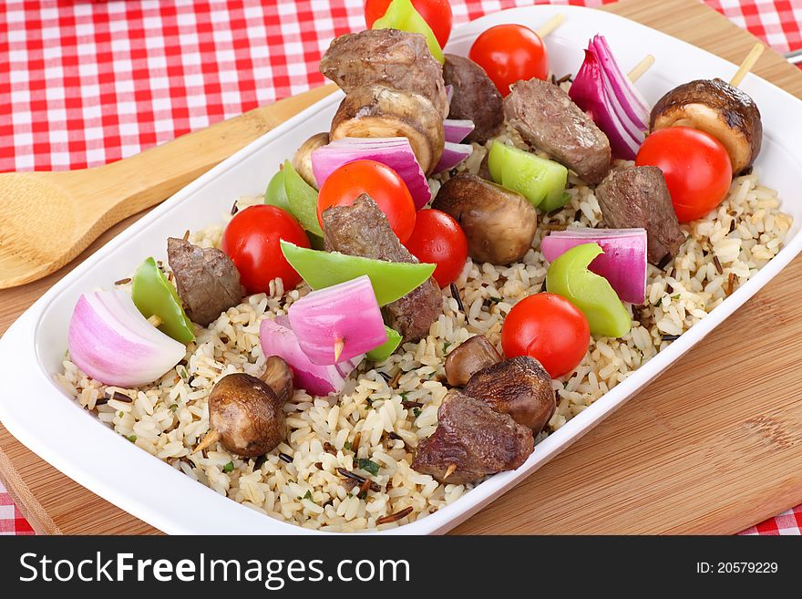 Beef and vegetable kabobs on top of rice