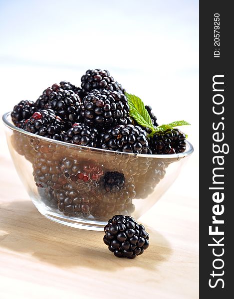 Fresh blackberries in a glass bowl on wooden table