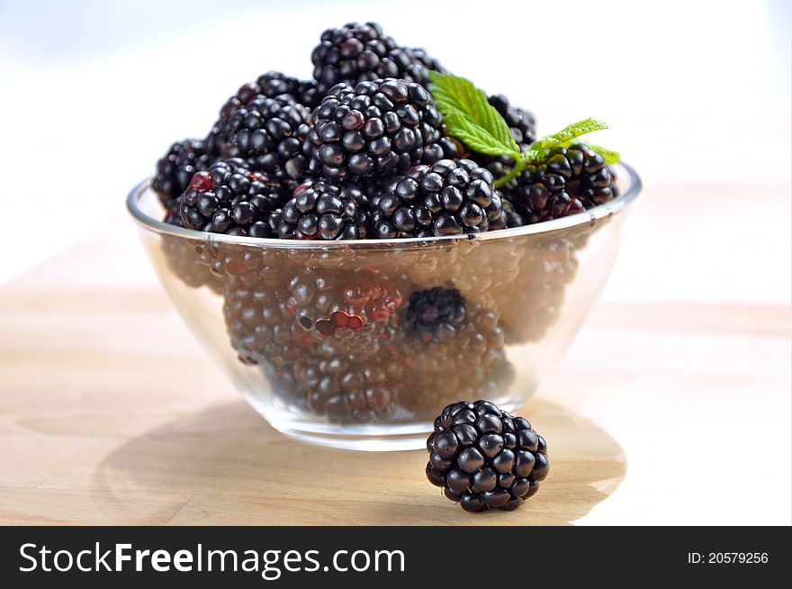 Fresh blackberries in a glass bowl on wooden table