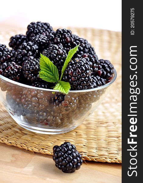 Fresh blackberries in a glass bowl on a straw mat