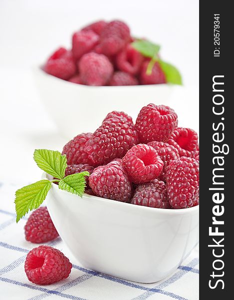 Two bowls of fresh raspberries on a napkin in a lattice. Two bowls of fresh raspberries on a napkin in a lattice