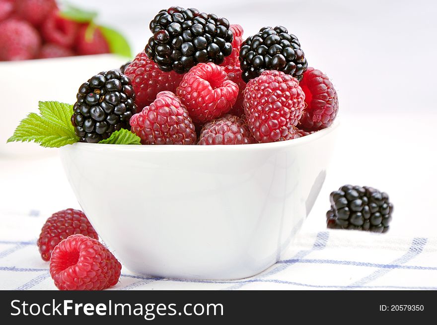 Raspberries and blackberries in a white bowl