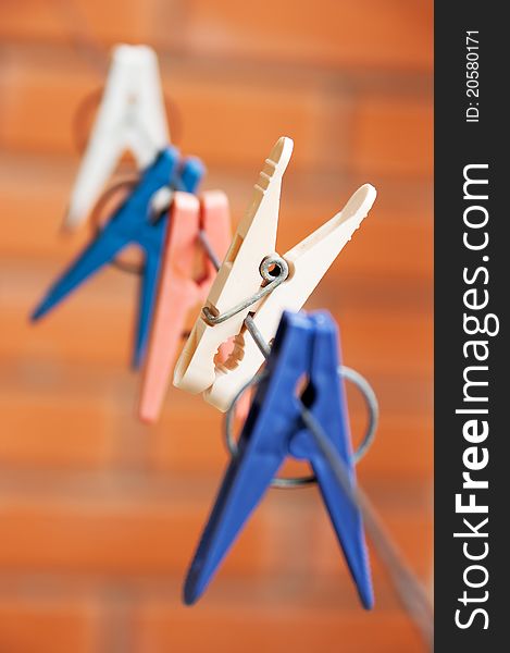 Colorful clothespin hanging on a clothesline. Focus on one of them - white color.