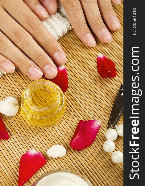 Close-up of girl lying on hand towel next to the cream, rose petals and manicure equipment. Close-up of girl lying on hand towel next to the cream, rose petals and manicure equipment