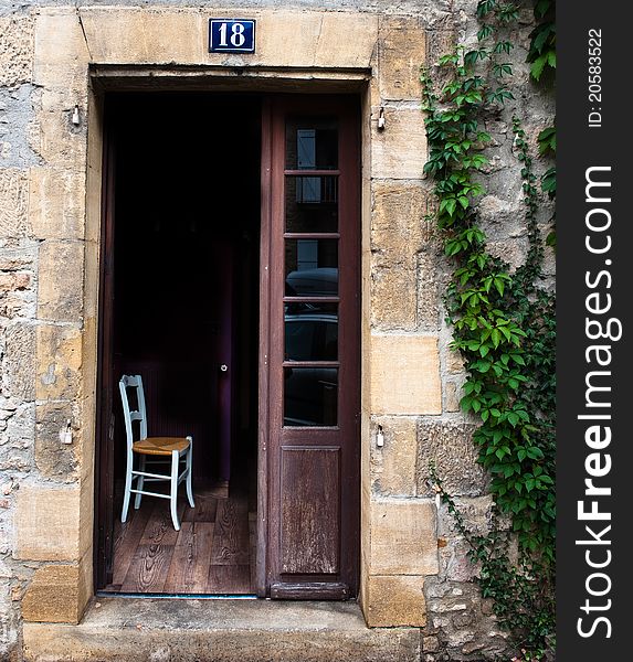 Single chair in an open doorway of a old French buildiing. Single chair in an open doorway of a old French buildiing