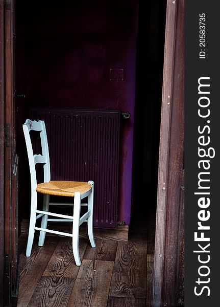 Single white chair in a doorway with purple background