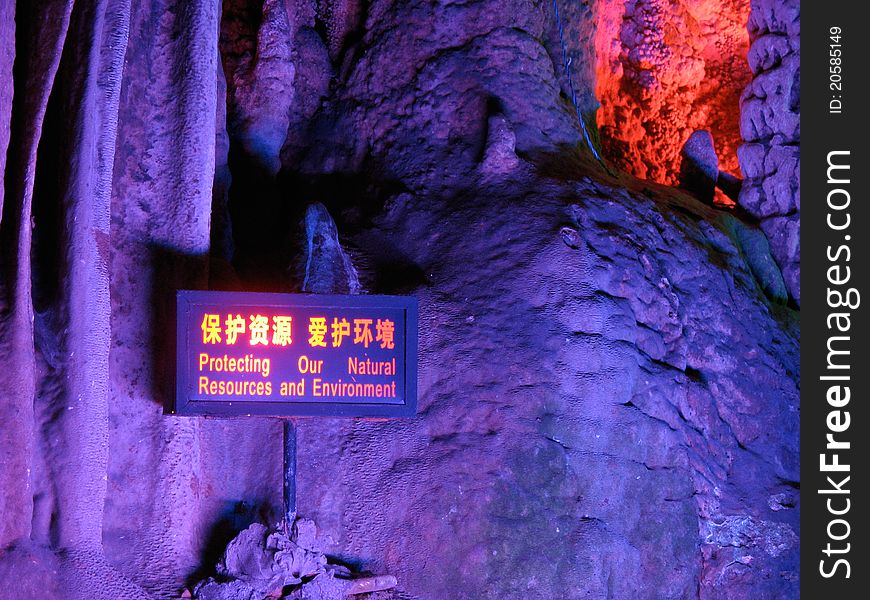 Stalactite with a sign board saying protect the environment, in the cave Yinziyan, Yangshuo, Guilin, China