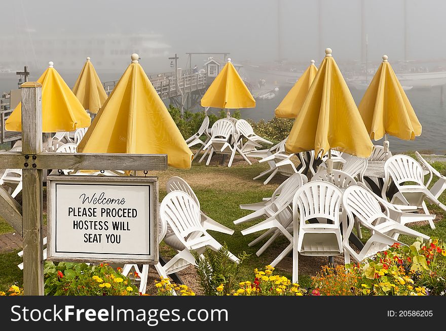 Outdoor cafe or restaurant welcome sign at a New England seaside resort. Ships in foggy background. Outdoor cafe or restaurant welcome sign at a New England seaside resort. Ships in foggy background.