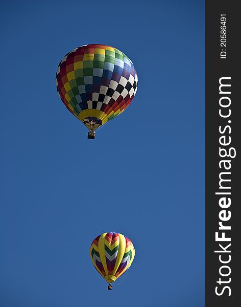 Two balloons soaring in a clear blue sky