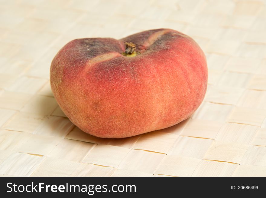 One fig shaped peach on wicher table