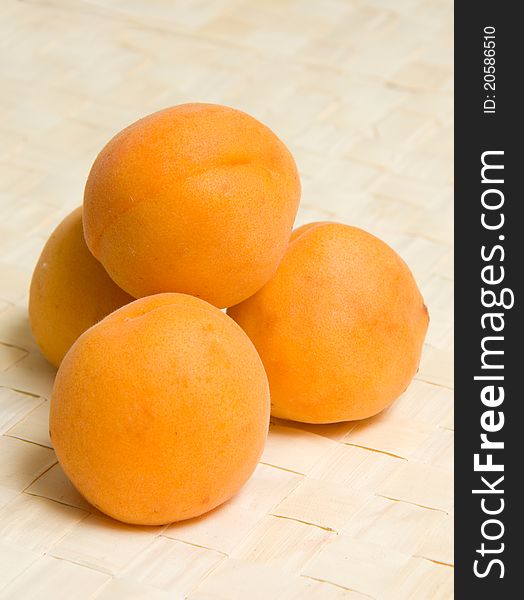 Four apricots on wicker table