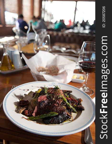 A meat meal served in a fine cuisine table of a restaurant with a cup of wine and blury background. A meat meal served in a fine cuisine table of a restaurant with a cup of wine and blury background.