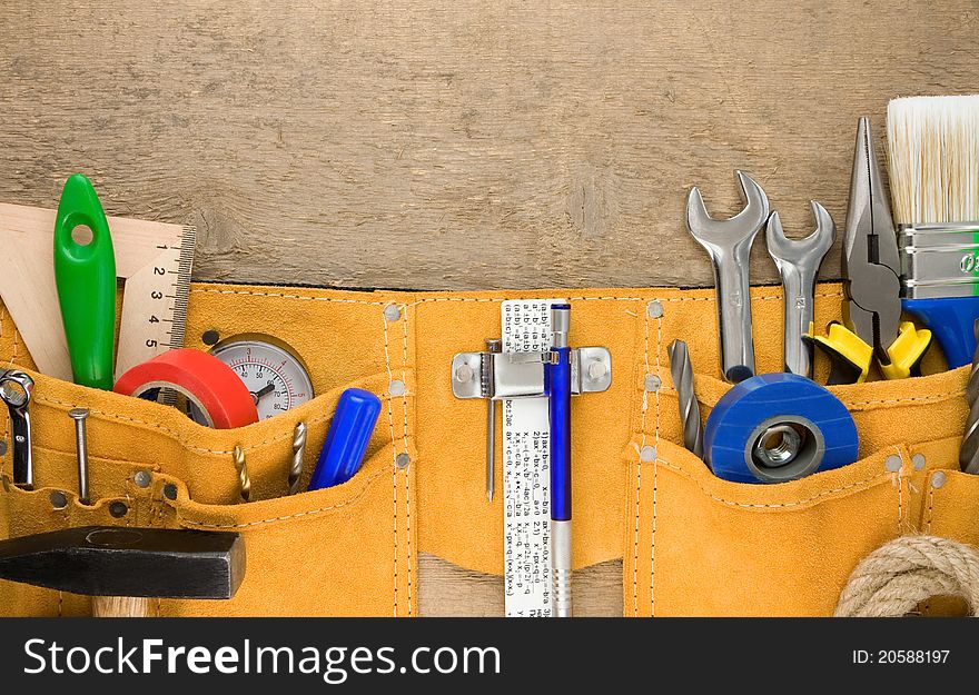 Set of tools in belt on wooden texture