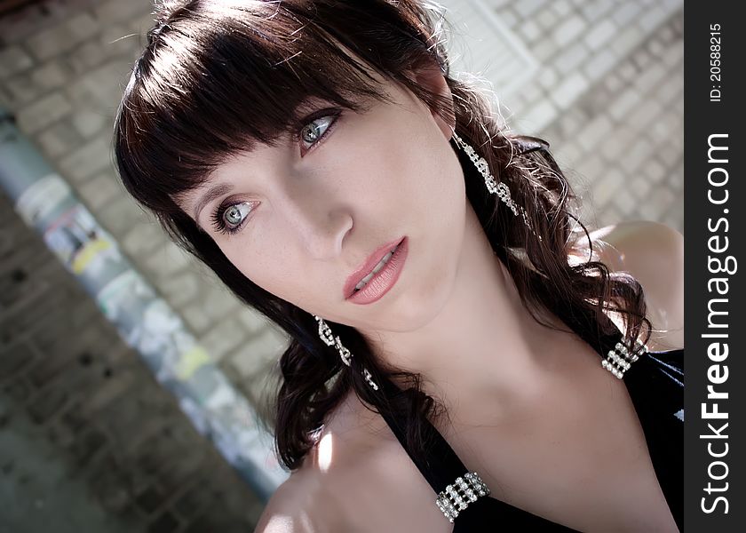 Beautiful young brunette girl poses in front of brick panted wall. Beautiful young brunette girl poses in front of brick panted wall