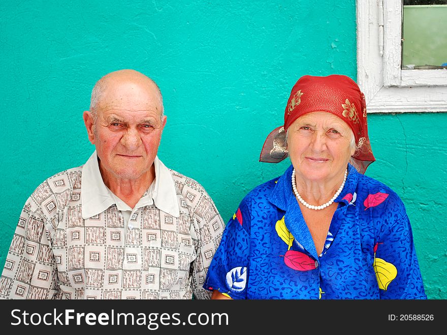 Old peasant couple with their old house in the background