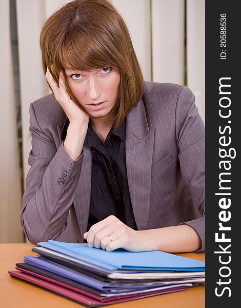 Overworked and frustrated woman with files on the desk. Overworked and frustrated woman with files on the desk
