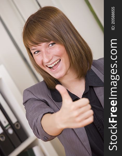 Happy businesswoman with thumb up gesture in office. Happy businesswoman with thumb up gesture in office