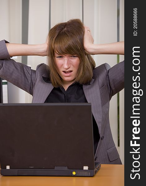 Stressed businesswoman holding her head with both hands looking at laptop. Stressed businesswoman holding her head with both hands looking at laptop