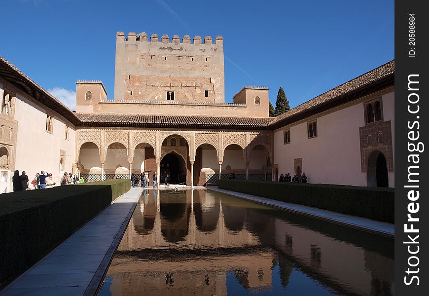 Water in a courtyard inside the Alhambra palace reflecting its surroundings in early morning light.