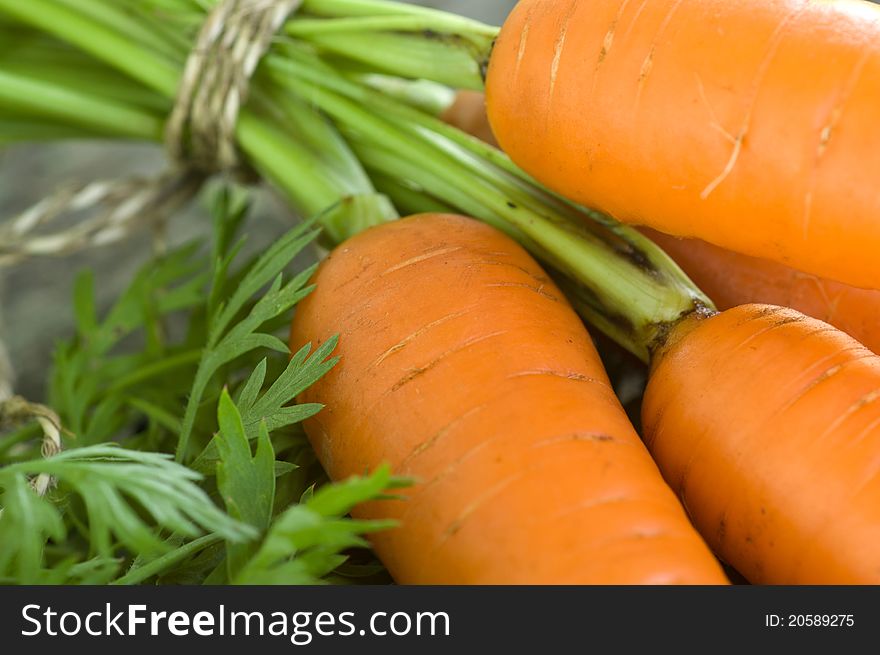 Raw carrot with leaves on wooden background. Raw carrot with leaves on wooden background