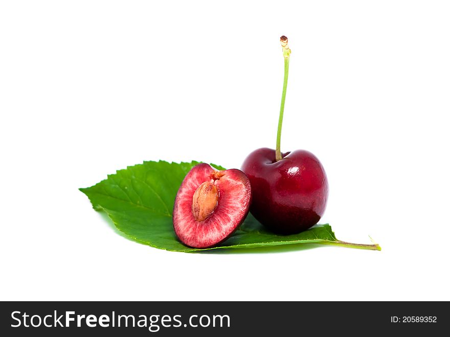 One red cherry and a half on a leaf  on white