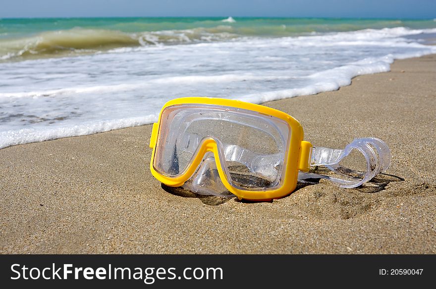 Yellow swimming mask on sea beach